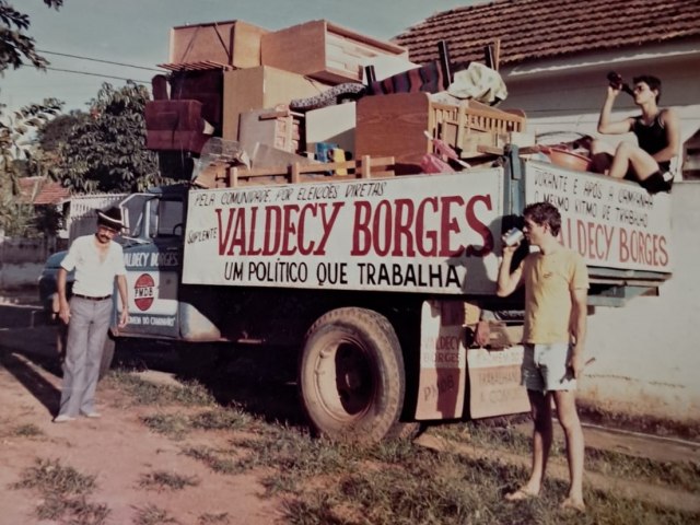 Fotografia antiga de Valdecy Borges em campanha, ao lado de um caminhão de mudança com sua faixa de candidato